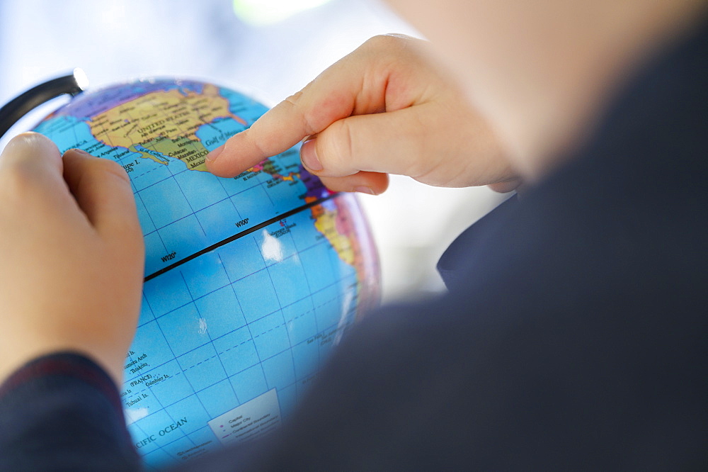 Close-up of boy (6-7) pointing at globe