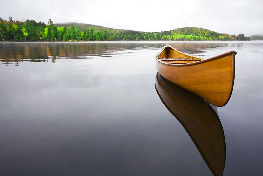 United States, New York, Saranac Lake, Wooden canoe floating on calm Upper Saranac Lake