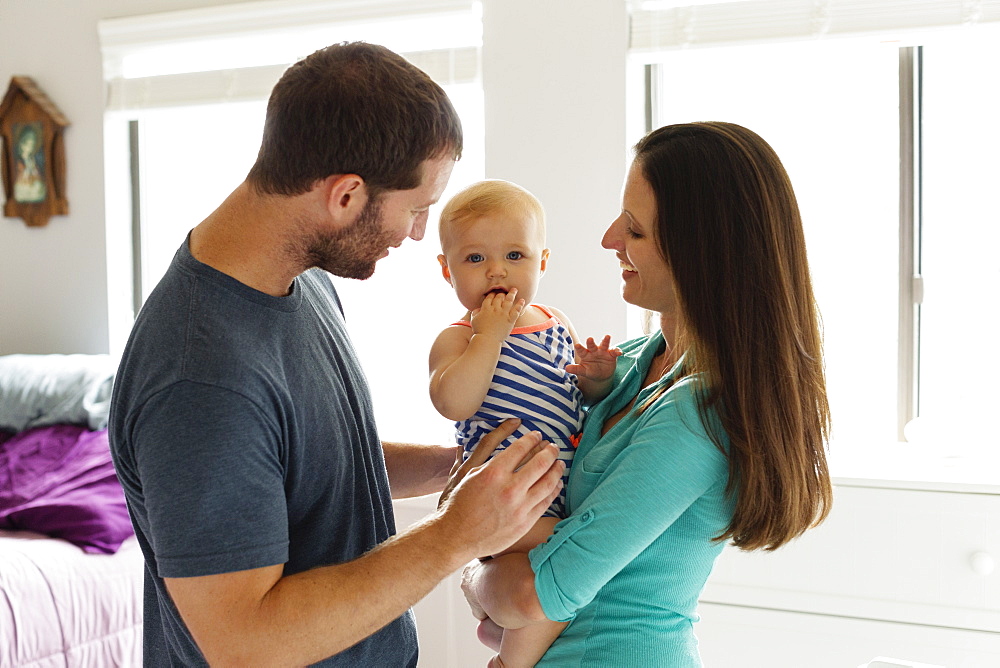 Portrait of mid adult couple with baby daughter in bedroom