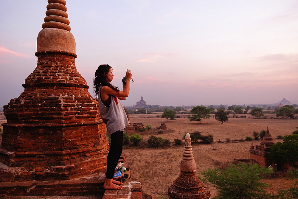 Woman taking photograph of view, Bagan Archaeological Zone, Buddhist temples, Mandalay, Myanmar