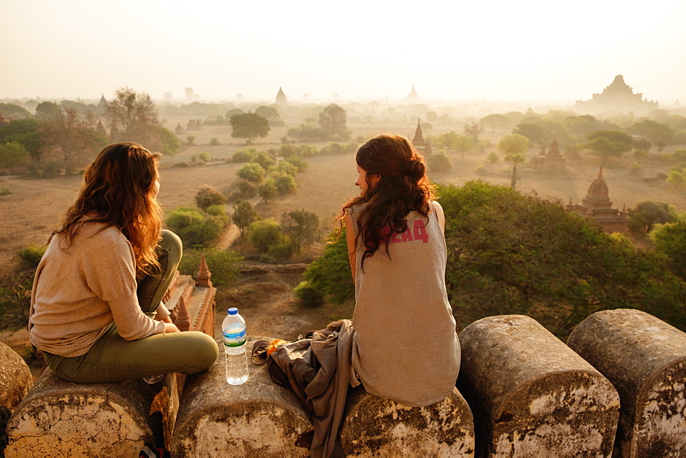 Women relaxing on stone wall, Bagan Archaeological Zone, Buddhist temples, Mandalay, Myanmar