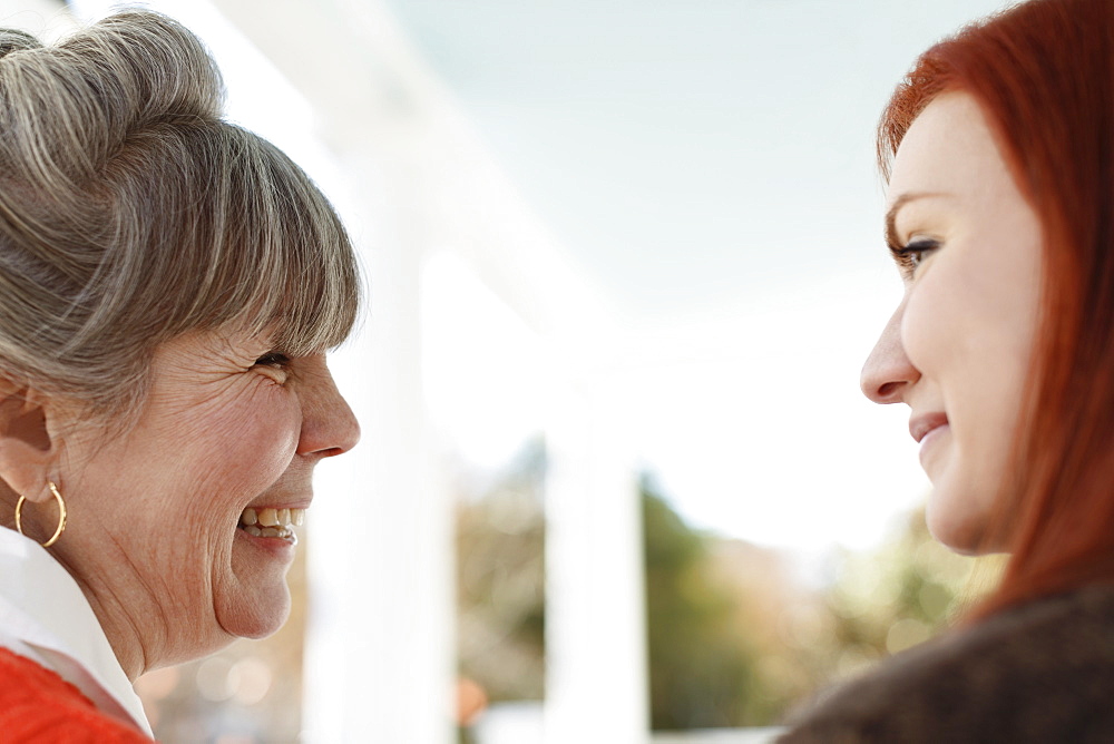 Close up of senior woman and adult daughter laughing on porch