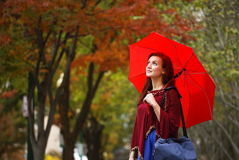 Young woman with red hair, holding red umbrella