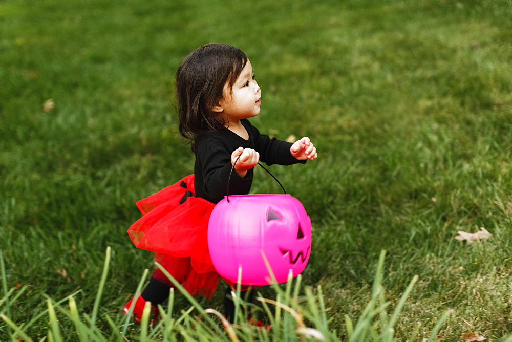 Girl in fancy dress costume with trick or treat bucket