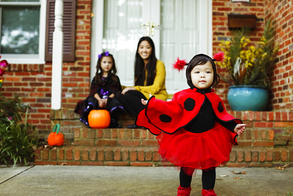 Girl dressed as ladybird outside house