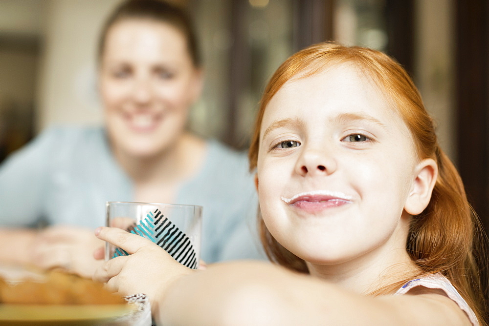 Girl with a milk moustache at dining room table