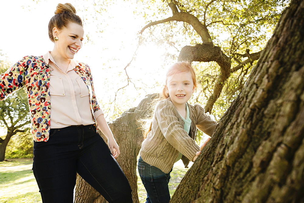 Portrait of mid adult mother watching daughter climb tree