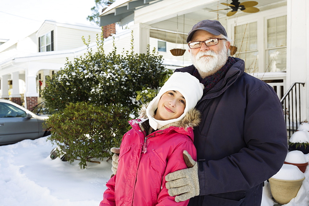 Grandfather and granddaughter outside house in winter