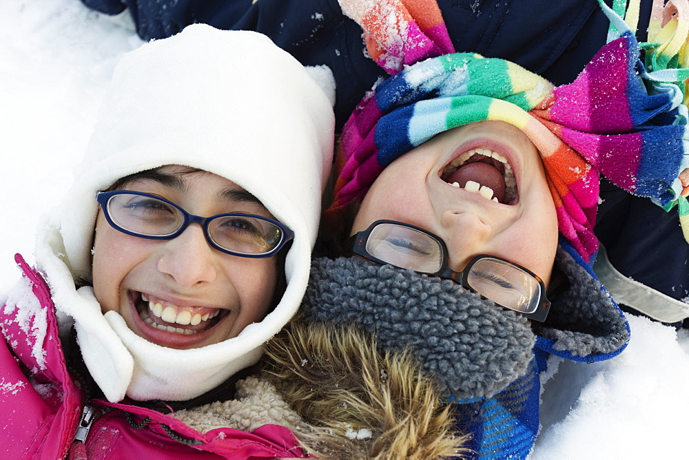 Boy and girl wearing winter hats and glasses, laughing
