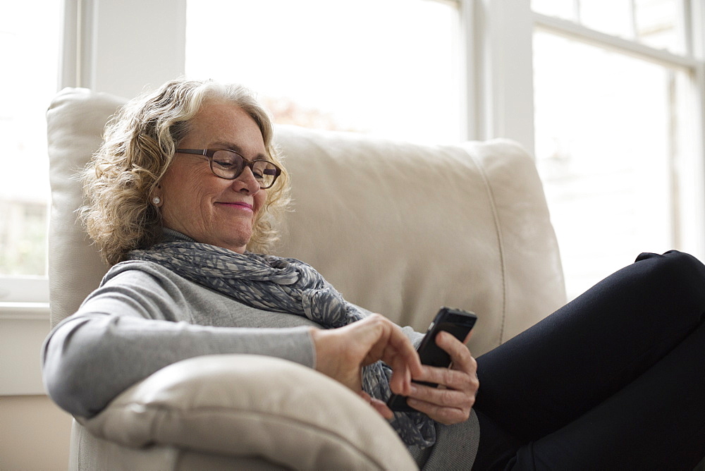 Senior woman relaxing on chair with mobile phone