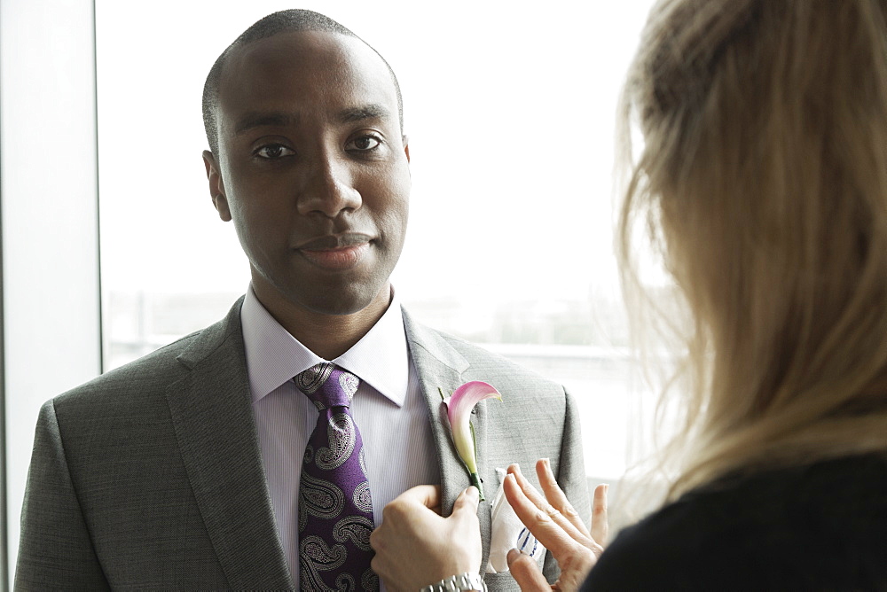 Bridegroom getting ready with help from friend