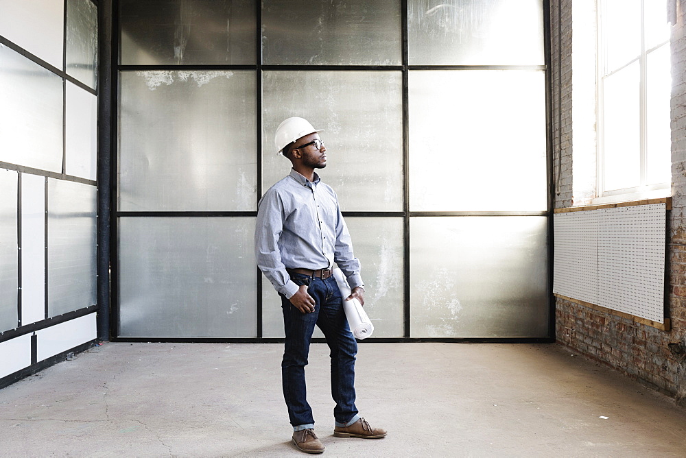 Portrait of young male interior designer in empty room