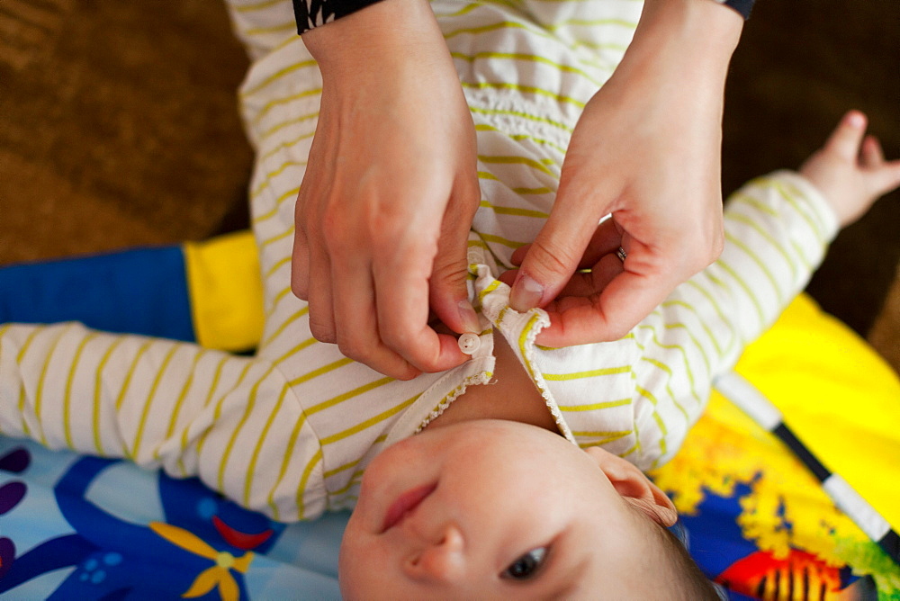 Close up of mother dressing baby daughter