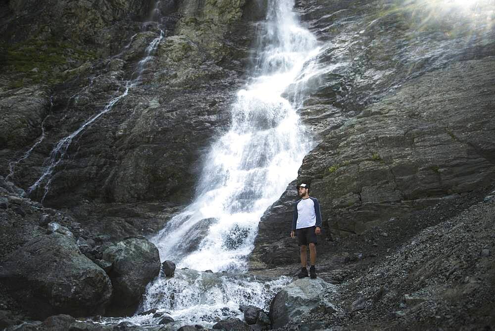 Russia, Karachay-Cherkessia, Arkhyz, Man standing near Sofiyskiye Vodopady waterfall in Caucasus Mountains