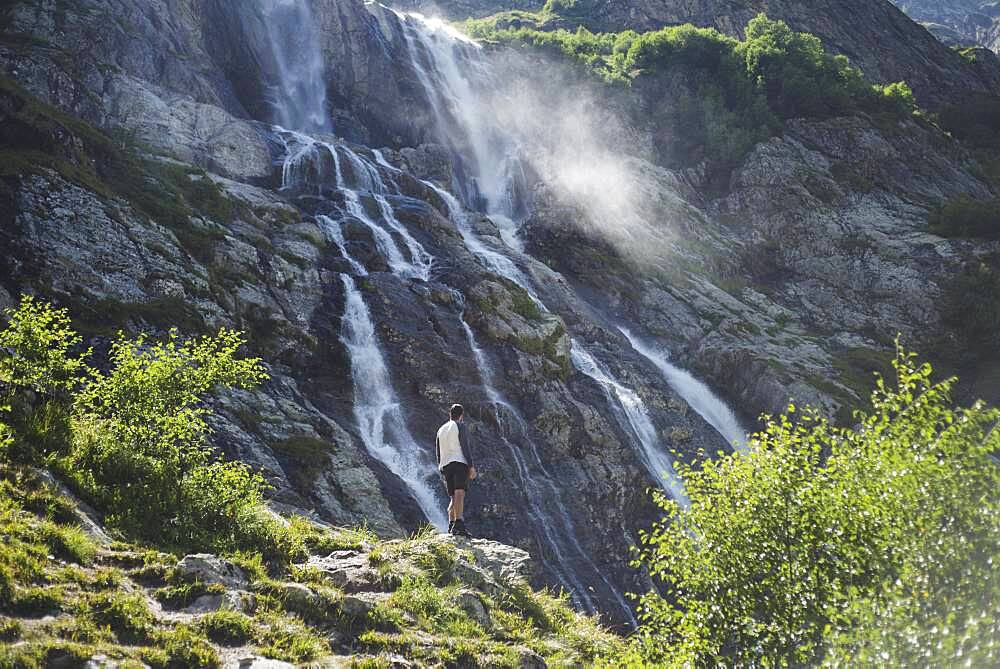 Russia, Karachay-Cherkessia, Arkhyz, Man standing near Sofiyskiye Vodopady waterfall in Caucasus Mountains