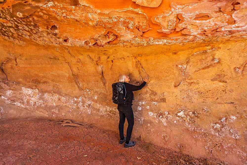 USA, Utah, Escalante, Woman touching sandstone cave wall in Grand Staircase-Escalante National Monument