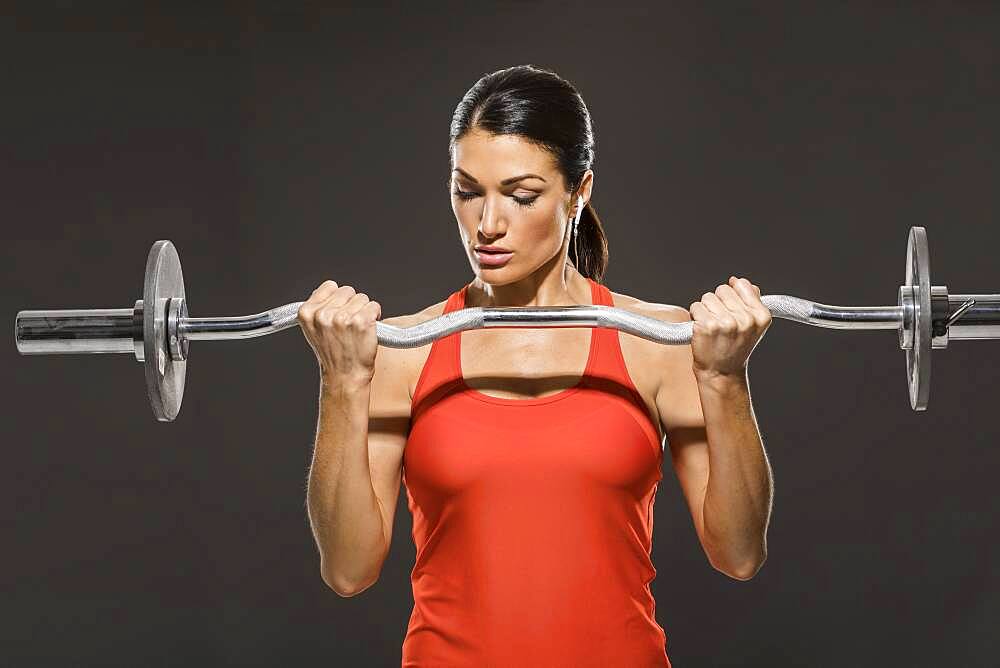 Athletic woman in red sleeveless top weight training