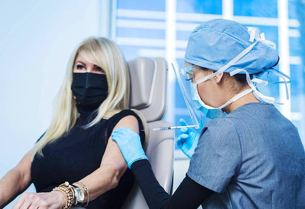 Woman in face mask receiving Covid-19 vaccination