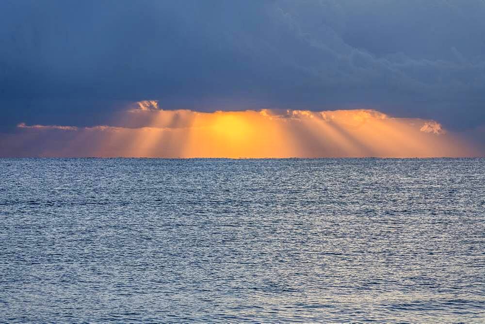 USA, Florida, Boca Raton, Sunbeams behind clouds above sea at sunrise