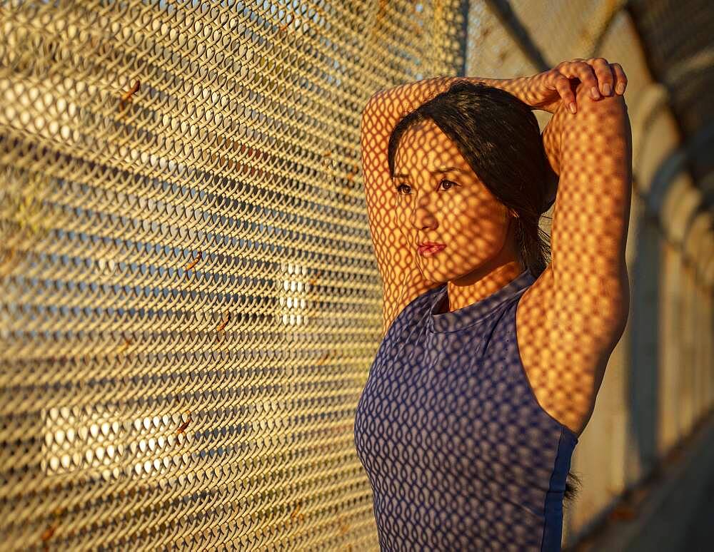 Athlete woman stretching at fence