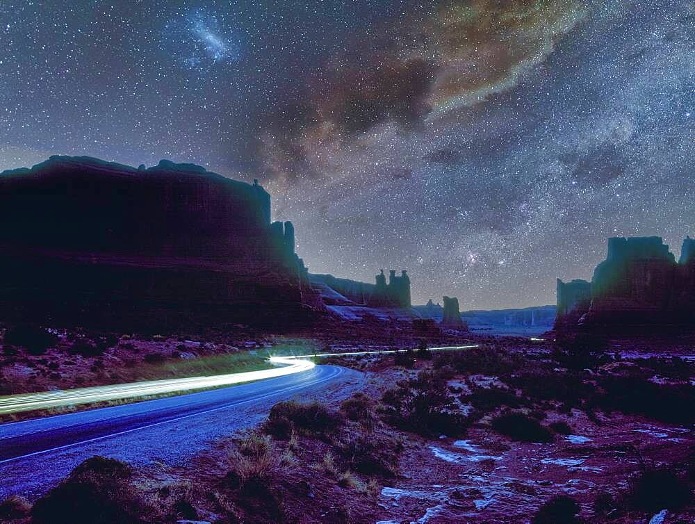 USA, Arizona, Monument Valley Tribal Park, Cars lights on dirt road in Monument Valley at night