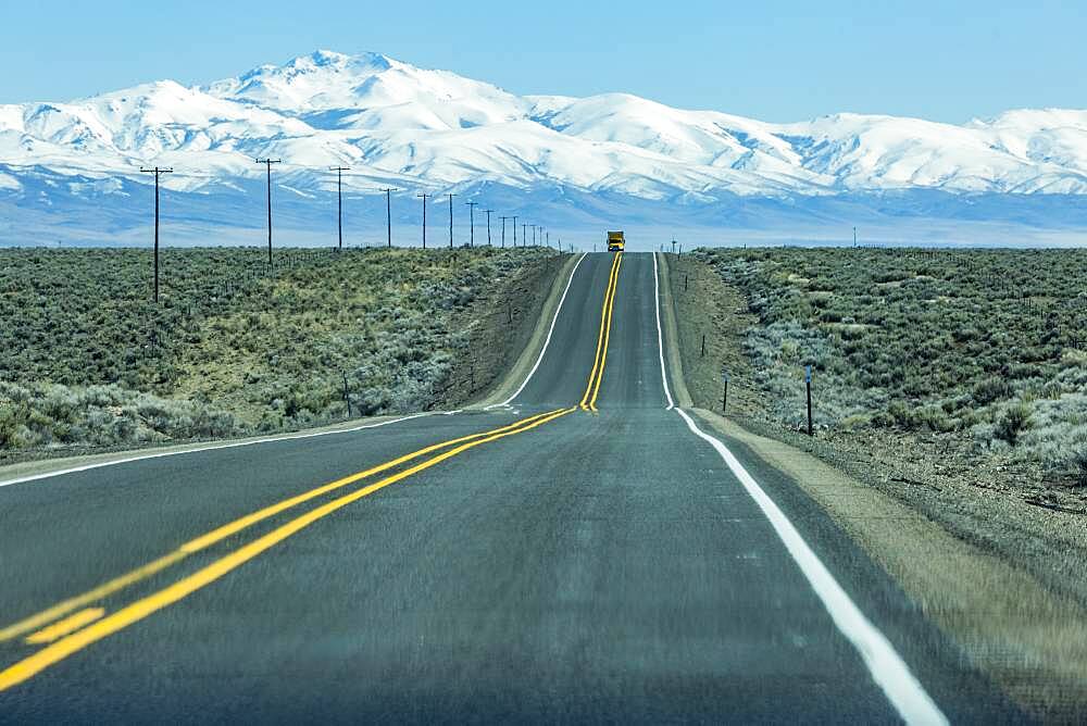 USA, Nevada, Winnemucca, Highway 95 crossing desert landscape with snowcapped mountains in distance