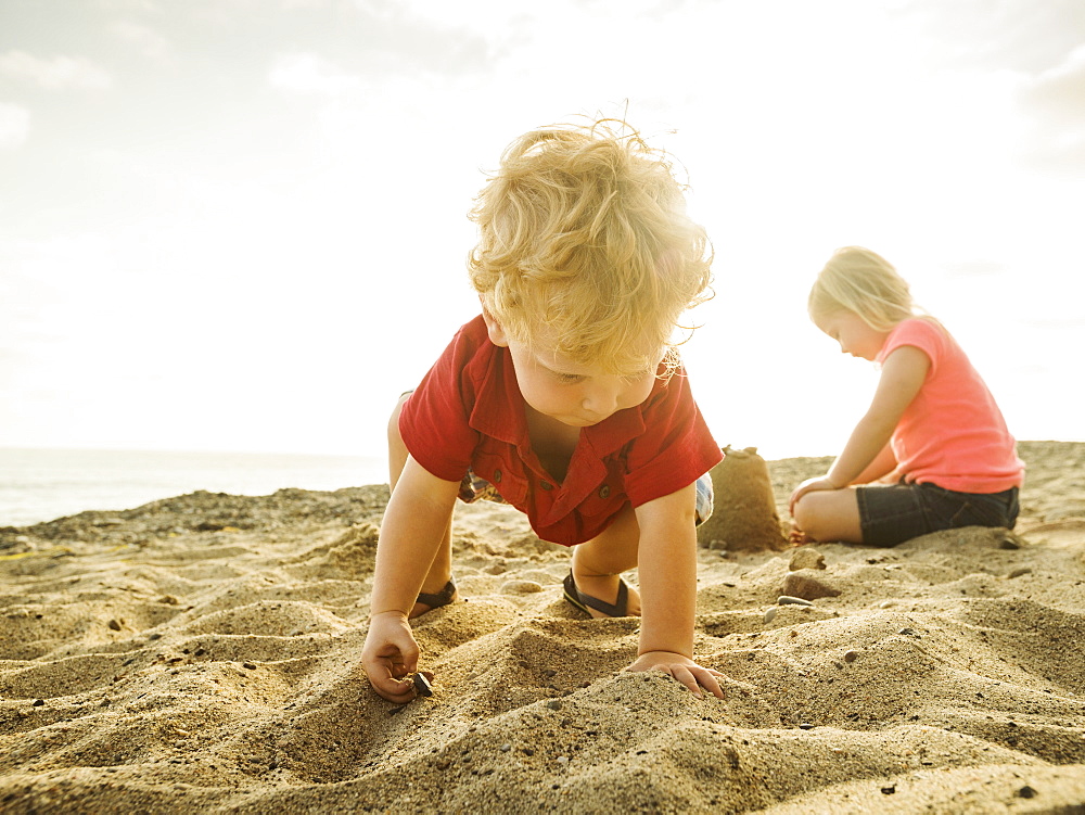 Girl (4-5) and boy (2-3) playing on beach, San Clemente, California