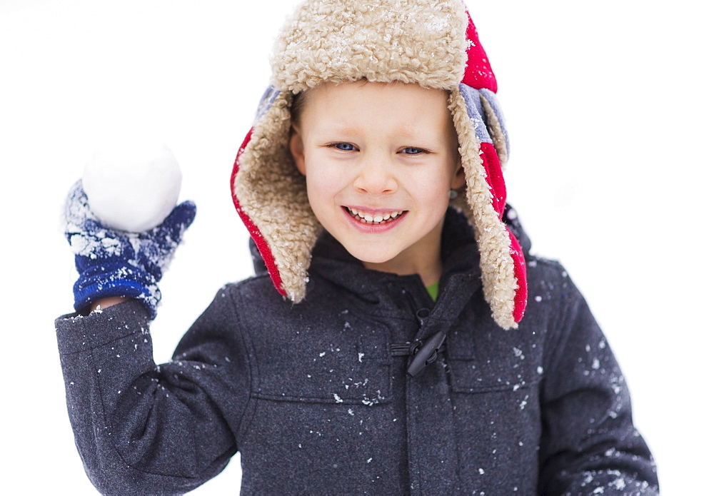 Boy (6-7) playing with snowball