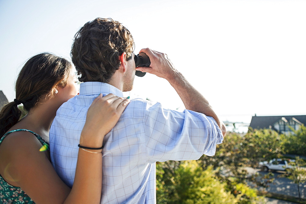 Rear view of couple, man looking through binoculars, USA, Washington, Everett
