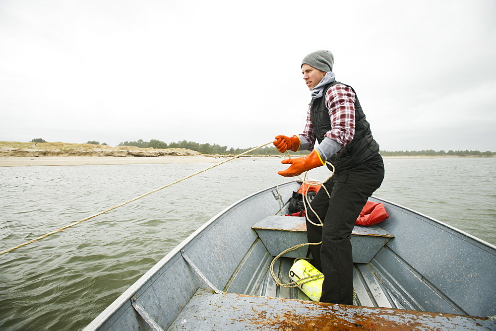 Man pulling net full of crabs, Rockaway Beach, Oregon