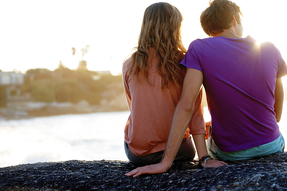 Rear view of young couple sitting at beach