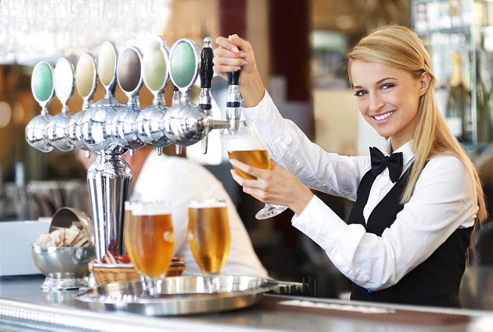 Female bartender pouring beer