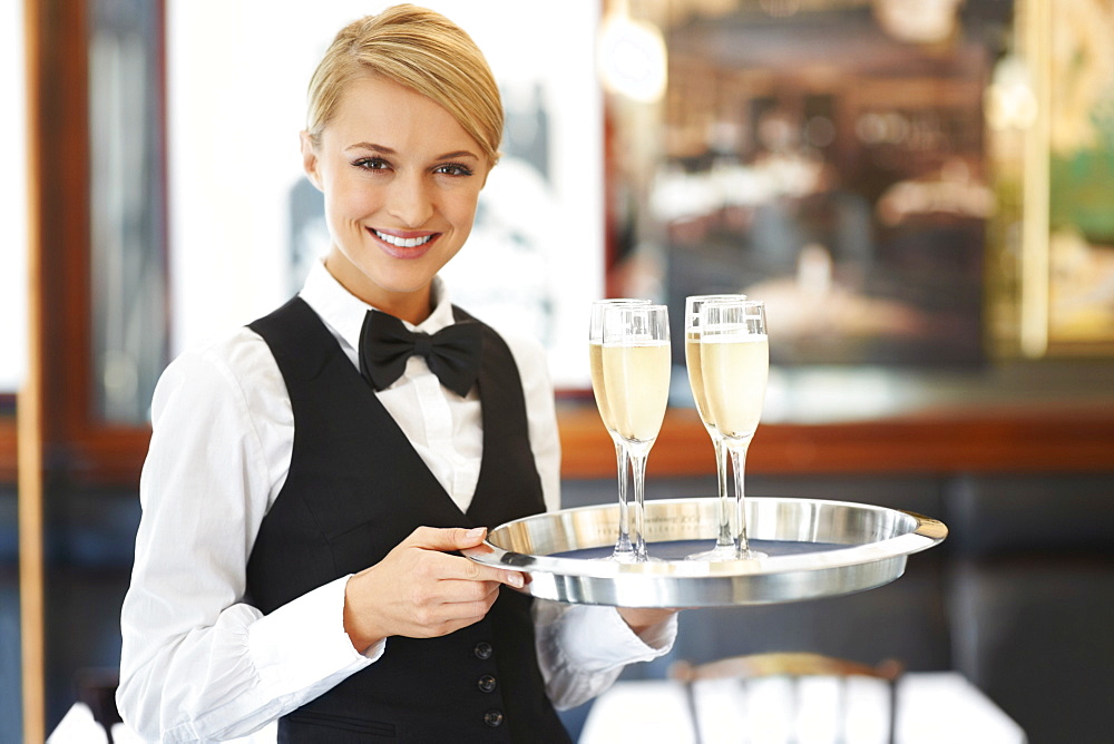 Portrait of waitress holding champagne flutes on tray