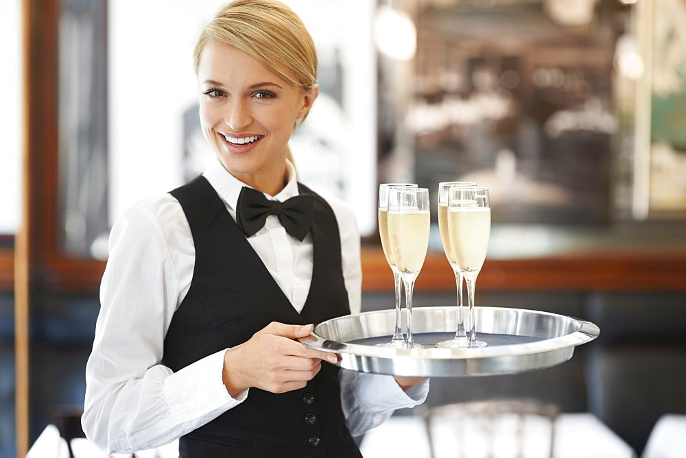 Portrait of waitress holding champagne flutes on tray