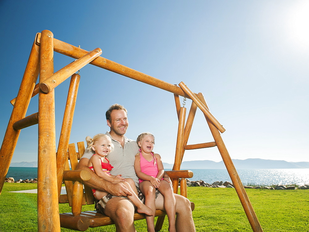 Father with daughters (2-3, 4-5) on swing, USA, Utah, Garden City