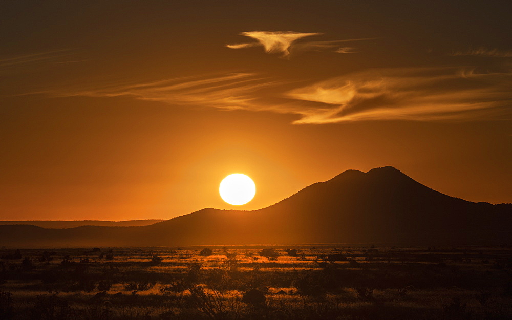 USA, New Mexico, Santa Fe, Sun setting above hill in Cerrillos Hills State Park