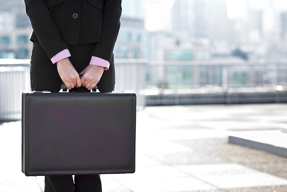 USA, Seattle, Midsection of businesswoman holding briefcase