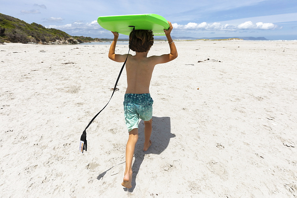 Boy (8-9) with surfboard on beach