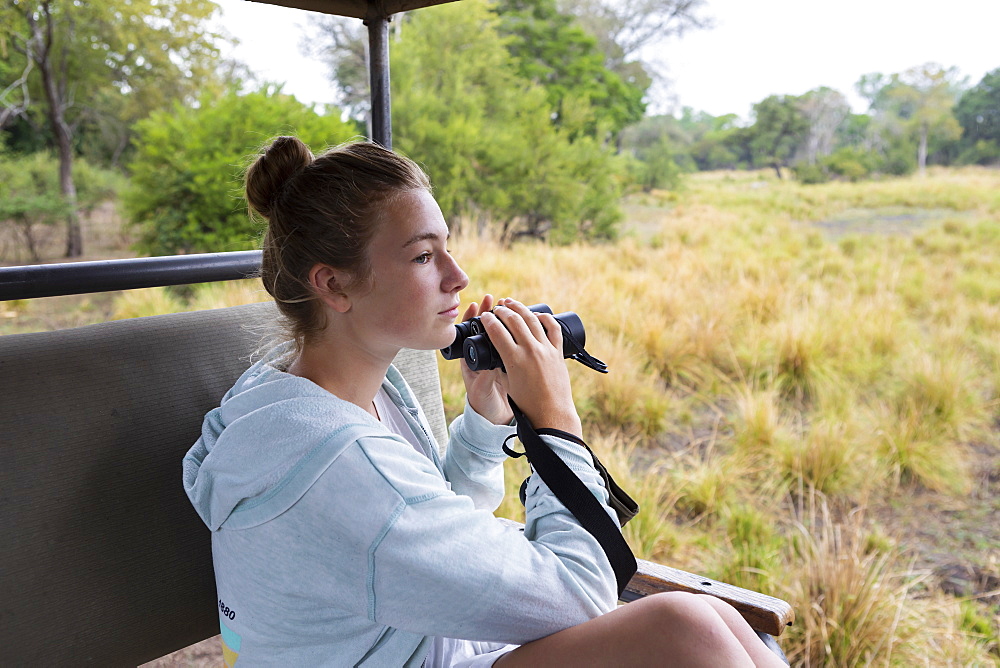 Africa, Zambia, Livingstone, Girl (16-17) in safari vehicle using binoculars