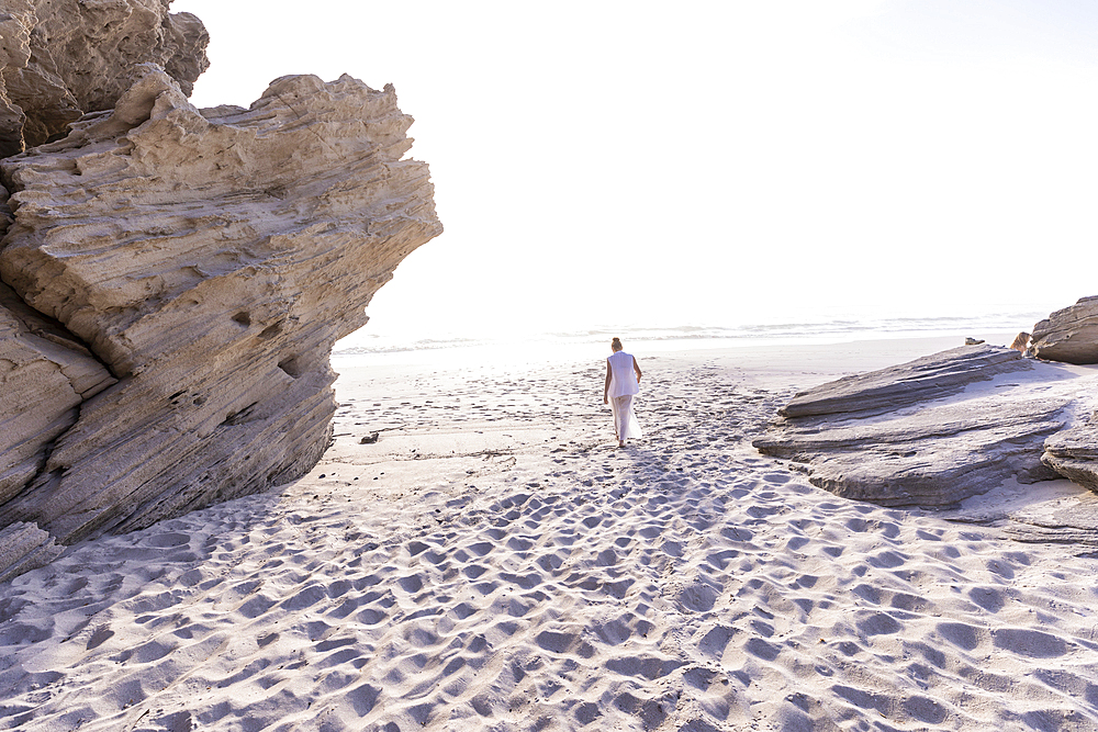 South Africa, Hermanus, Girl (16-17) walking on Sopiesklip beach in Walker Bay Nature Reserve