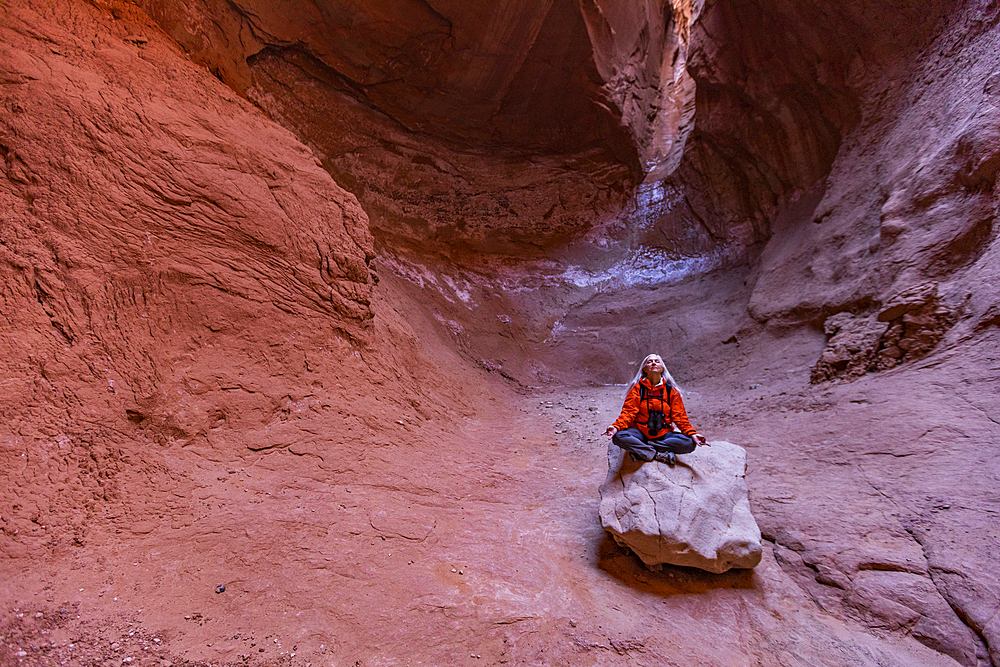 United States, Utah, Escalante, Senior female hiker sitting on rock in canyon