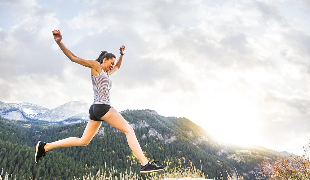 United States, Utah, American Fork, Woman jogging in mountain landscape at sunset