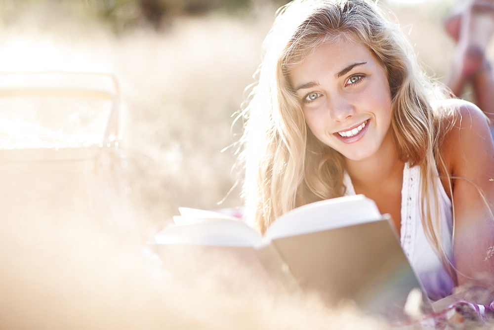 Teenage girl (16-17) posing for portrait while reading book outdoors