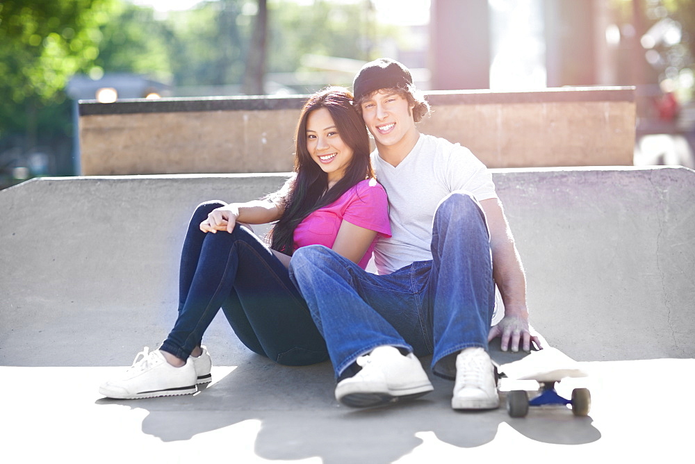 Young multi-racial couple posing with skateboard