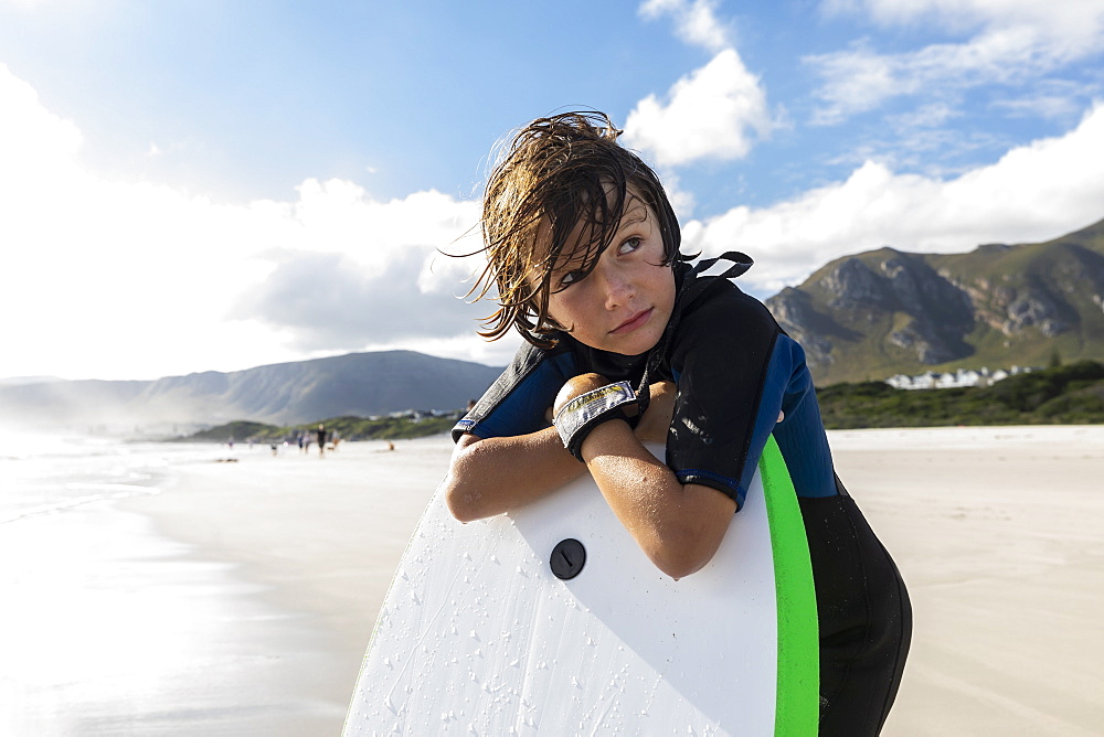 South Africa, Hermanus, Boy (8-9) resting on his surfboard