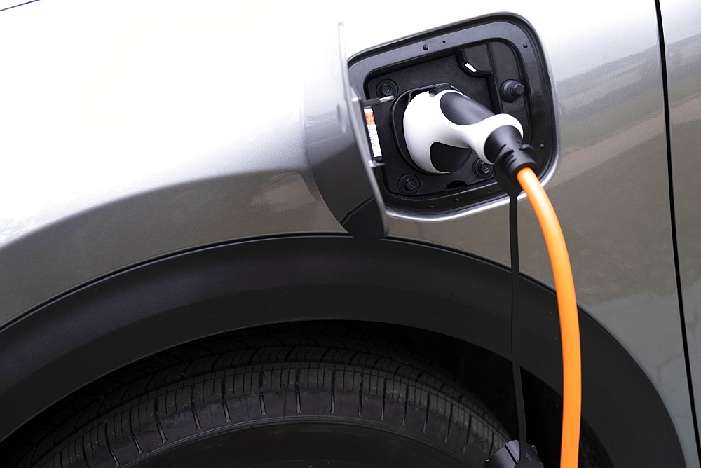 Close-up of electric car being charged with plug-in power cord