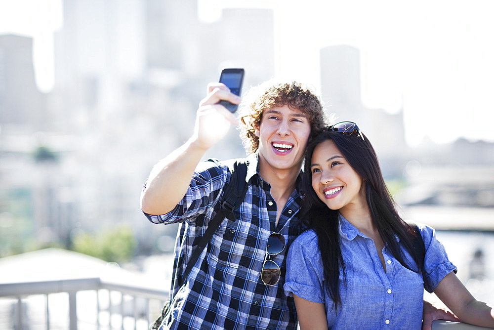 USA, Washington, Seattle, Couple wearing sunglasses photographing themselves with smart phone