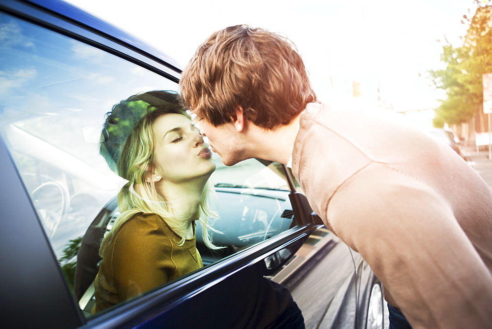Young couple kissing through window of car