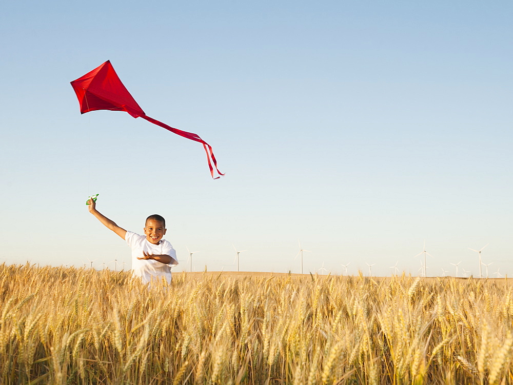 Boy (10-11) playing with kite in wheat field