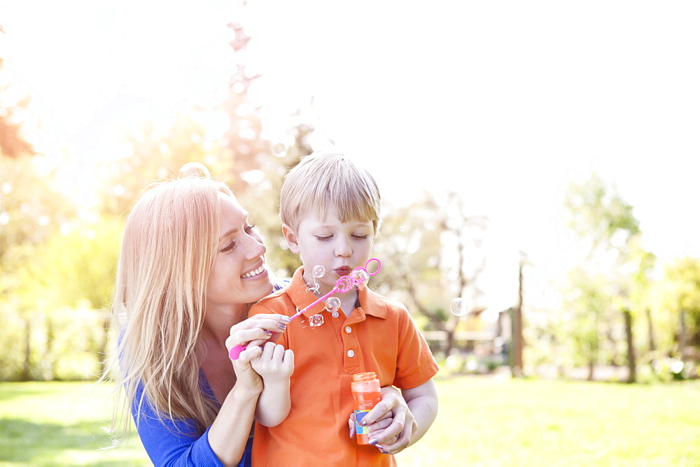 Mother and son (2-3) blowing bubbles in park